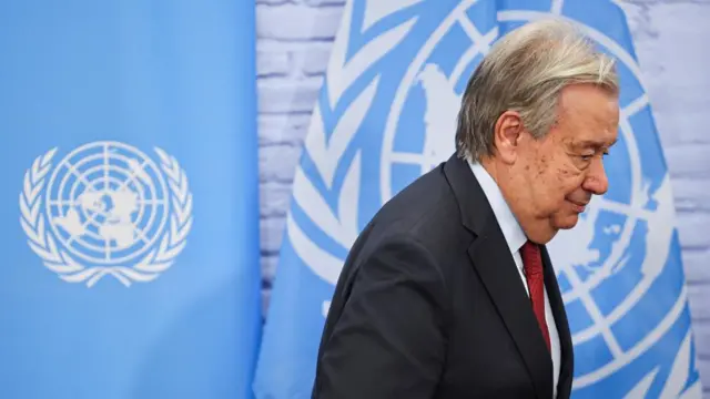 UN Secretary-General Antonio Guterres is pictured walking in front of United Nations flags