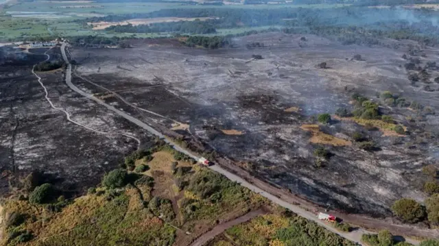 An overhead view of scorched landscape with smoke still rising