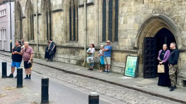 Clusters of people are shown standing on the street near Hull Crown Court.