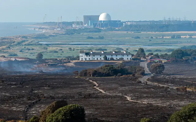A wide shot with Dunwich Heath in the foreground, with blackened ground showing signs of fire, and Sizewell nuclear plant (white dome at the centre) in the background