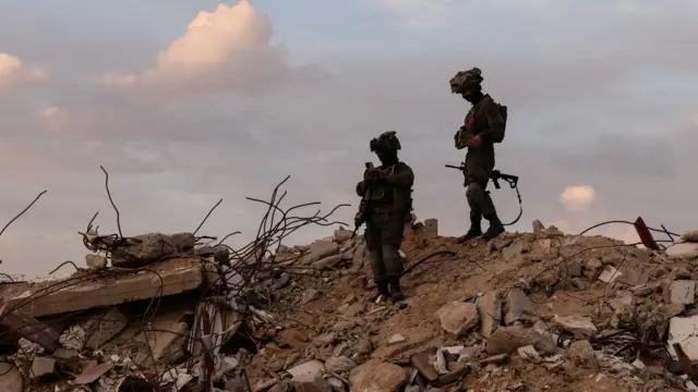 Israeli soldiers stand on rubble in Rafah in the southern Gaza Strip, December 8, 2025.