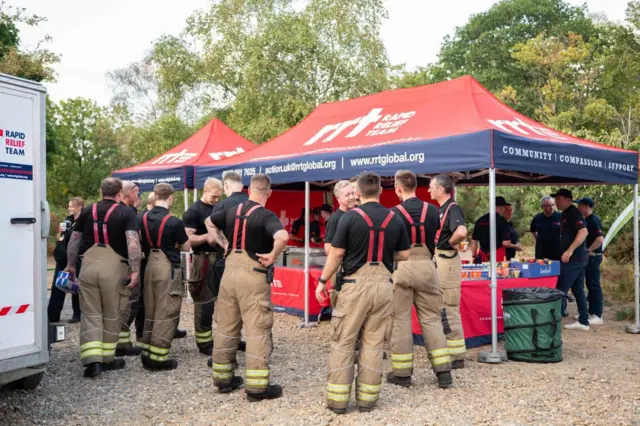 Firefighters are standing near a refreshment station