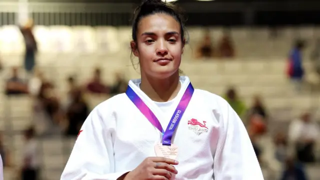 Lele Nairne stands on the podium with her bronze medal