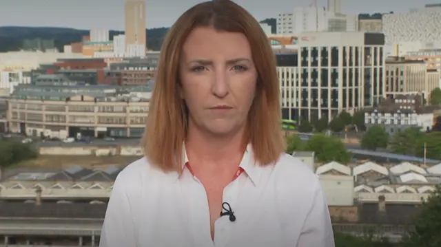 Louise Haigh speaking to BBC breakfast wearing a white shirt with a city backdrop