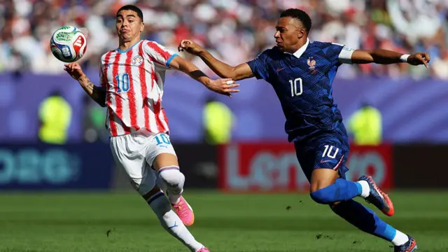 Miguel Almiron competes for the ball against Kylian Mbappe