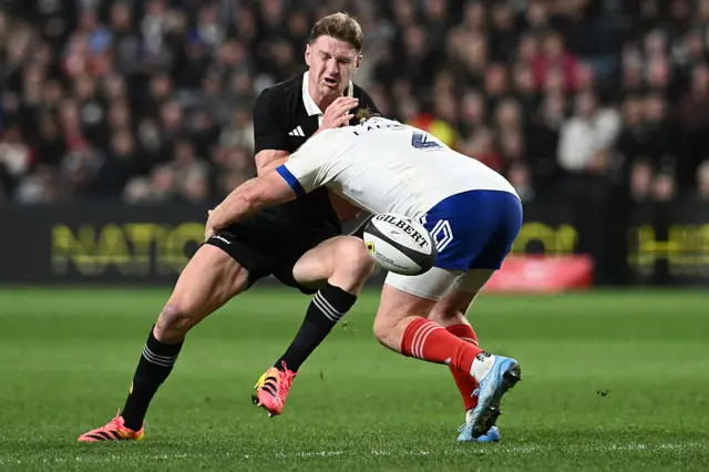 New Zealand's Jordie Barrett is tackled by France's Maxime Lamothe