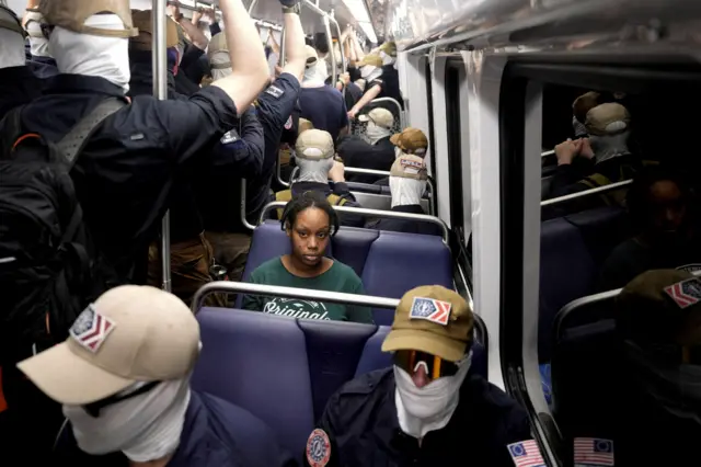 A commuter sits as members of the group Patriot Front ride the metro