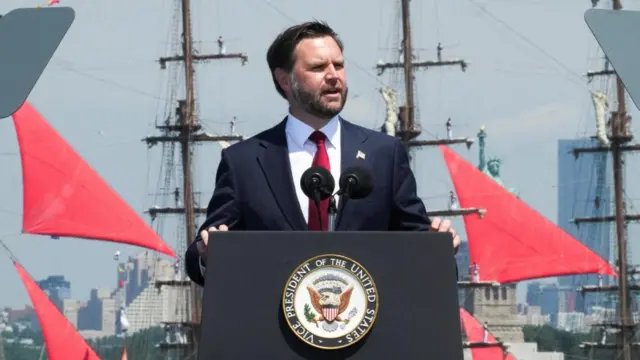 JD Vance delivers a speech on the USS Kearsarge. The Statue of Liberty and a boat with red sails can be seen behind him