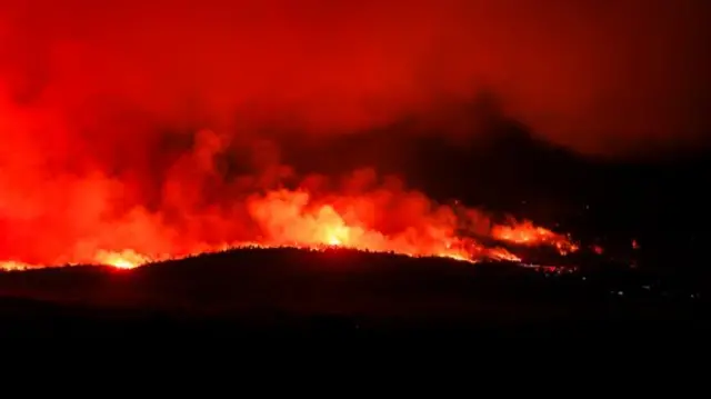 Bright red flames and thick smoke are seen on grass lands in the Aspen Acres in Rye, Colorado