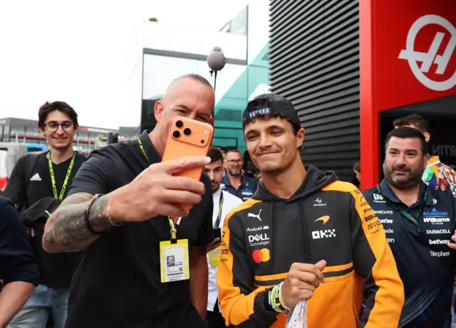 Lando Norris takes a picture with fans