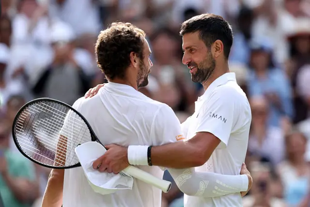 Novak Djokovic hugs Roman Safiullin at the net