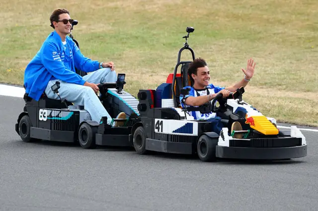 George Russell and Arvid Lindblad and George Russell drive during the Lego parade
