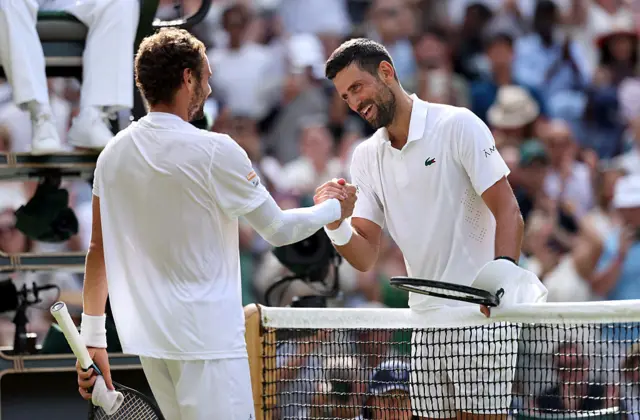 Novak Djokovic shakes hands with Roman Safiullin at the net