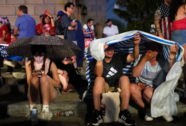 People in Washington, DC huddle on the steps in the rain