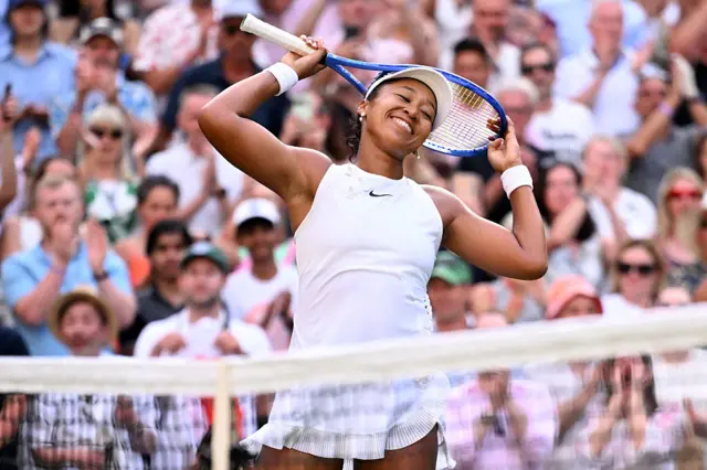 Naomi Osaka holds a tennis racquet on her head