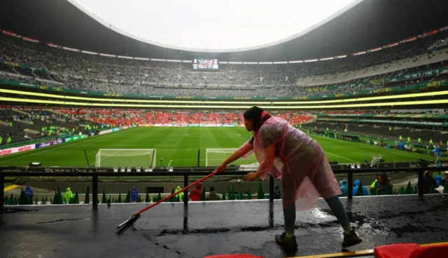 Stadium official uses a squeegee to scrape water