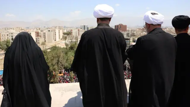 Iranians watch the funeral ceremony of the late Iranian Supreme Leader, Ayatollah Ali Khamenei, from the roof of a building in Tehran