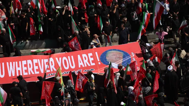 Iranians hold a banner as they take part in the funeral ceremony of the late Iranian Supreme Leader Ayatollah Ali Khamenei in Tehran