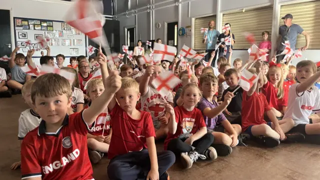 Children at Catleway Primary wear England shirts and wave flags
