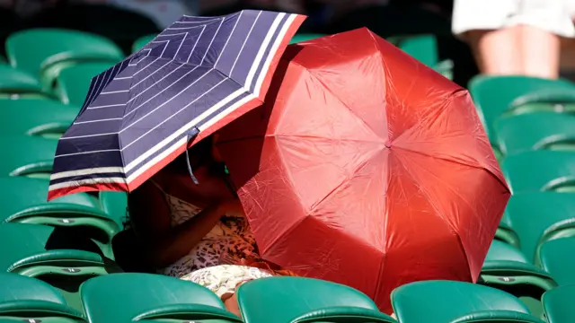 Fans shield from sun with umbrellas