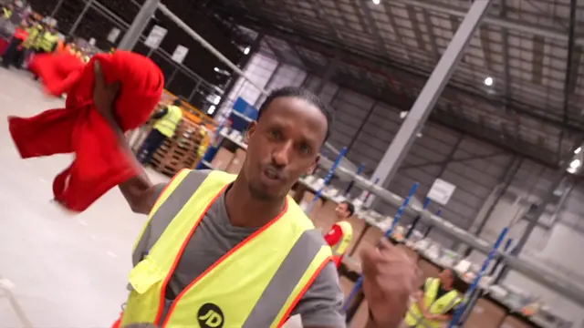 Nightshift worker holding red jumper and with a fist in the air