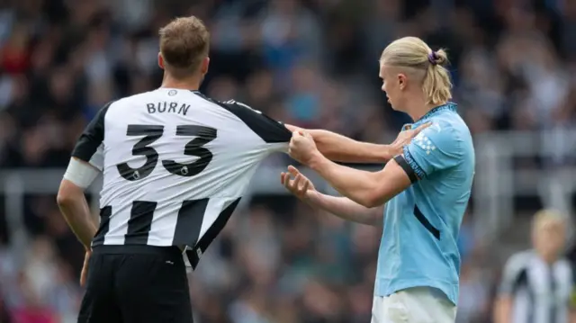 Erling Haaland of Manchester City pulls the shirt of Dan Burn of Newcastle United during the Premier League match between Newcastle United FC and Manchester City FC at St James' Park on September 28, 2024 in Newcastle upon Tyne, England