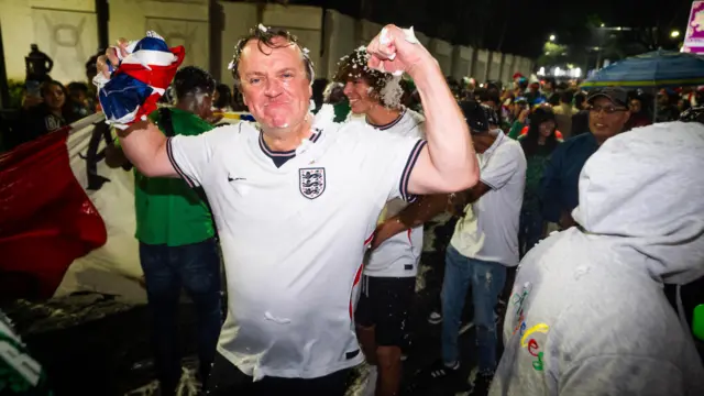England fan pumps arms as he's sprayed with foam