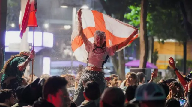 England fan carrying flag covered in foam