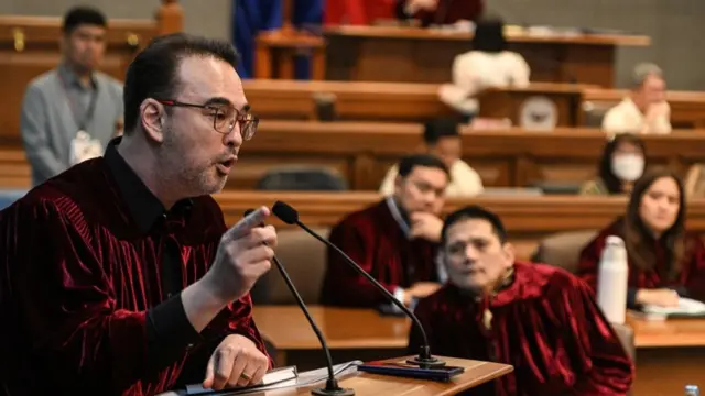 Philippine Senator Alan Peter Cayetano talks into a microphone, while other senators watch in the background