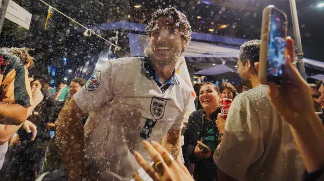 A man covered in foam in an England top in Mexico