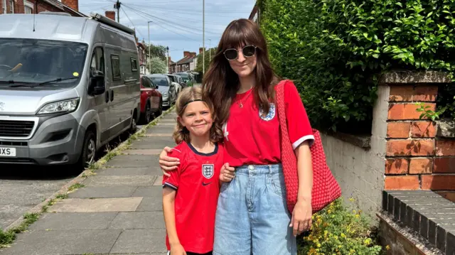 Jess Clarke posing with her son Wren. Both are wearing red England tops