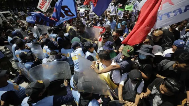 Crowd of protesters pushing against police with riot shields