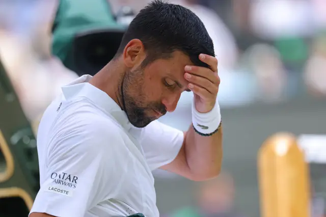 Novak Djokovic sitting down with his hand on his forehead