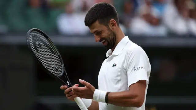 Novak Djokovic of Serbia looks at his hand