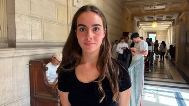 Amelina poses for a picture in the Palais de Justice. There are around dozen other people scattered behind her
