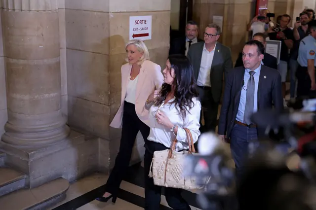 Marine Le Pen arriving at court with people in tow