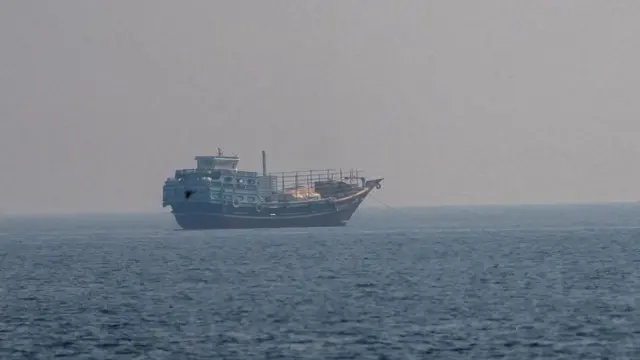 A ship seen floating in the sea. The sky above looks grey and cloudy.
