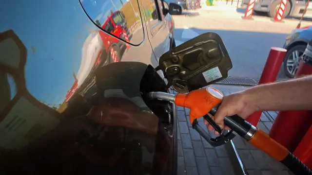 A man refuels his car at a petrol station.