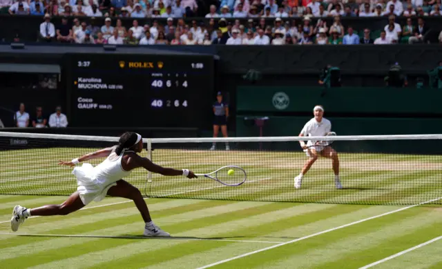 Coco Gauff stretches for a forehand with Muchova in the background