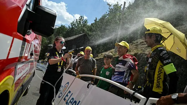 A firefighter spray water on spectators at the finish line of the Tour de France cycling race