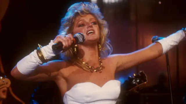 Bonnie Tyler, wearing a white outfit permining in Germany in 1990