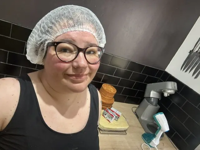 Melissa Jablonski smiling with a hairmask on in a kitchen, with cooking utensils behind her