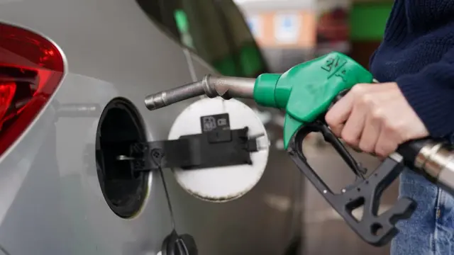 A man fills his car with fuel at a petrol station.