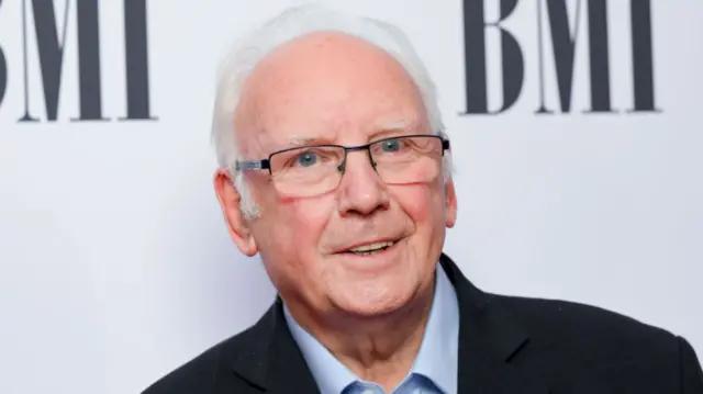 Pete Waterman is pictured in front of a white background, smiling to the camera.