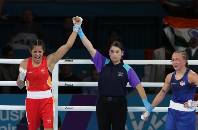 Sakshi Chaudhary's hand is held up as Ruby White looks upset
