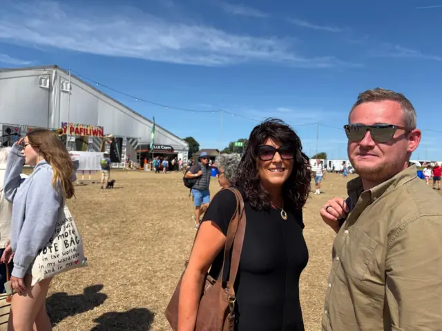 Gerallt Rhys Jones a Sara Meredydd o Gemaes a Phenegoes, Machynlleth - cartref eisteddfod 2027 yn ciwio i fynd i weld cystadleuaeth y corau yn y pafiliwn ac yn gobeithio am lwc dda i Aelwyd Penllys