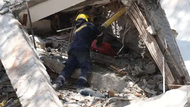 A member of the Cali Fire Department works among the rubble of buildings collapsed by a 7.4-magnitude earthquake in Cali, Colombia, 10 August 2026