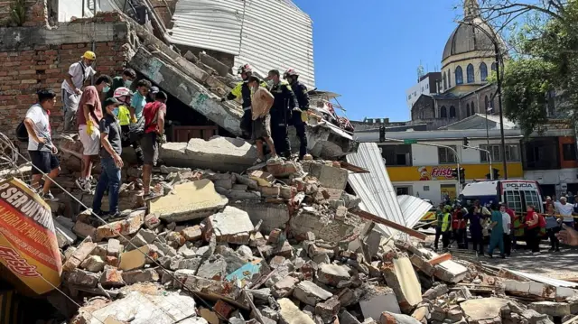 Residents and emergency personnel dig through the debris of a partially collapsed building after an earthquake, in Pereira, Colombia August 10