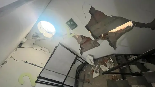 Damage to the inside of a building showing large cracks and wholes in the walls of a stairwell