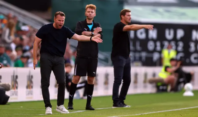 Tom Cleverley and Matt Taylor gesture from the touchline